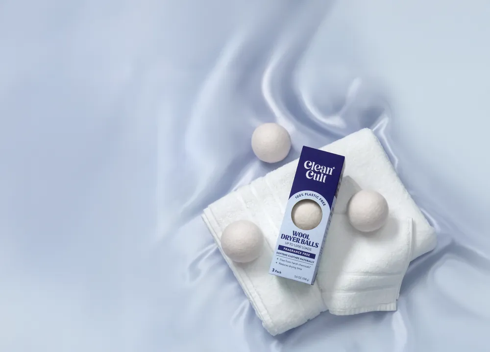 Three wool dryer balls and their box on folded white towels