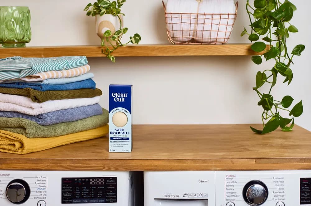 A box of wool dryer balls on a laundry room shelf above the washer and dryer