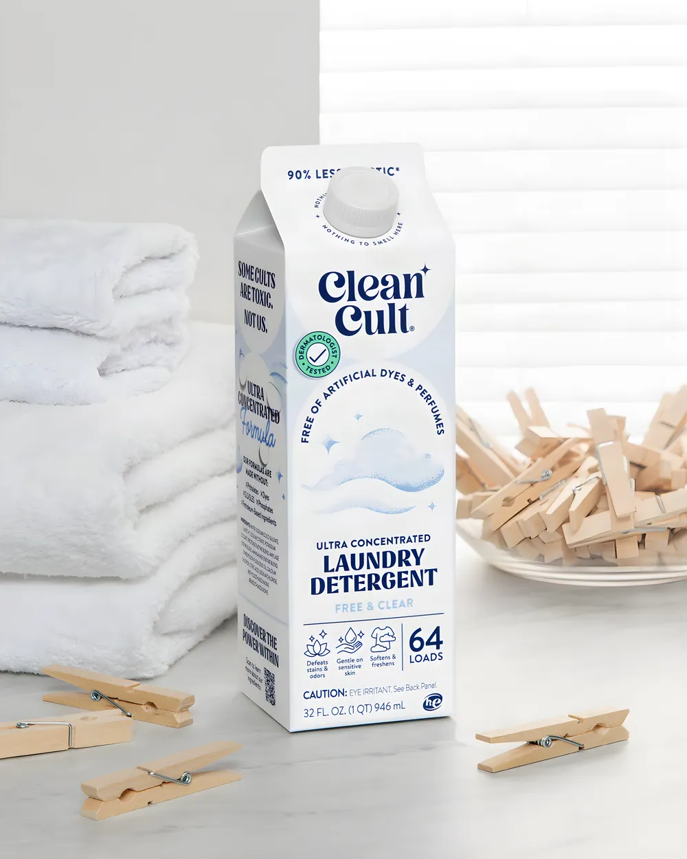 A carton of Free & Clear detergent with folded towels and wooden clothespins