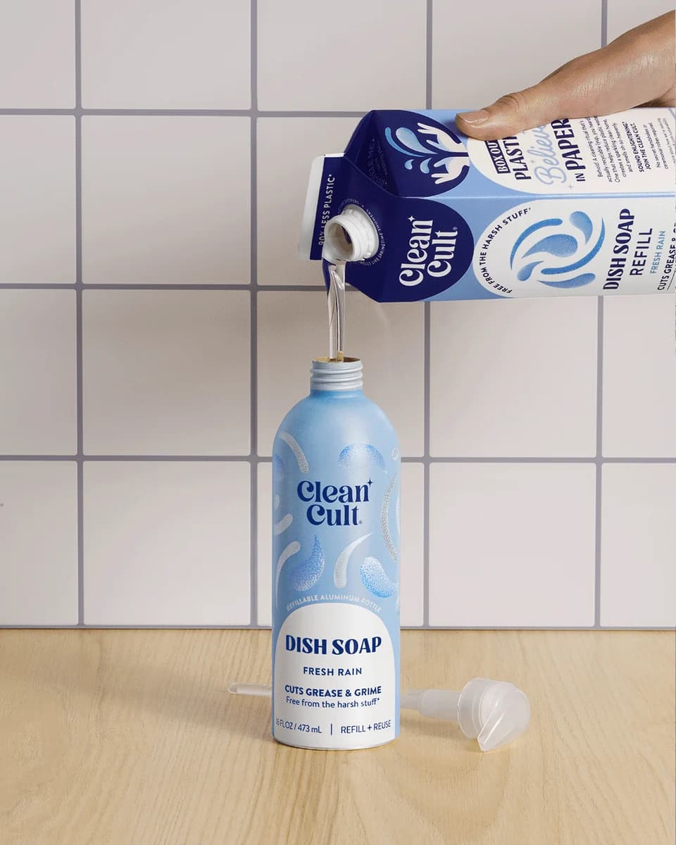 Pouring a dish soap refill carton into an aluminum dish soap bottle