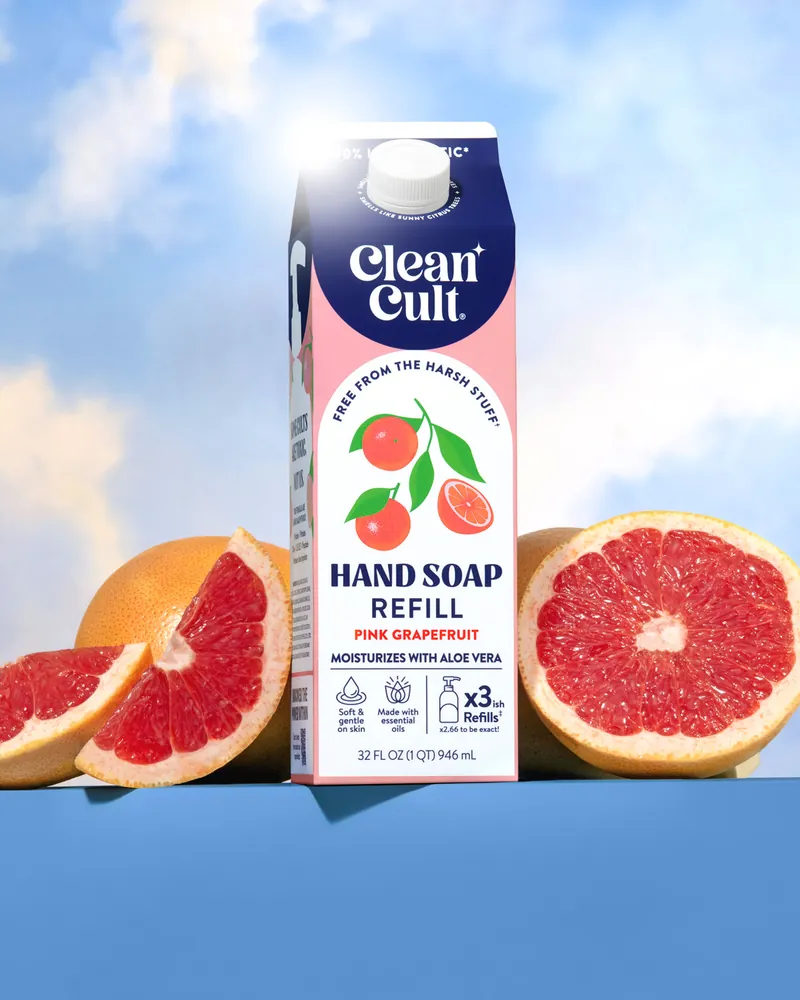 A Pink Grapefruit hand soap refill between two halves of a grapefruit