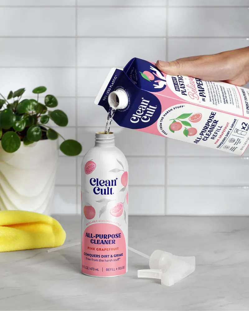 Pouring an all-purpose cleaner refill into a pink aluminum spray bottle